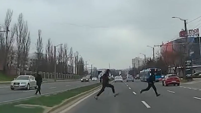 Momentul în care trei indivizi aleargă printre mașini pe viaduct